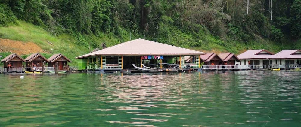 A serene lakeside resort with colorful cabins nestled among lush greenery offers a tranquil escape for nature lovers seeking relaxation.