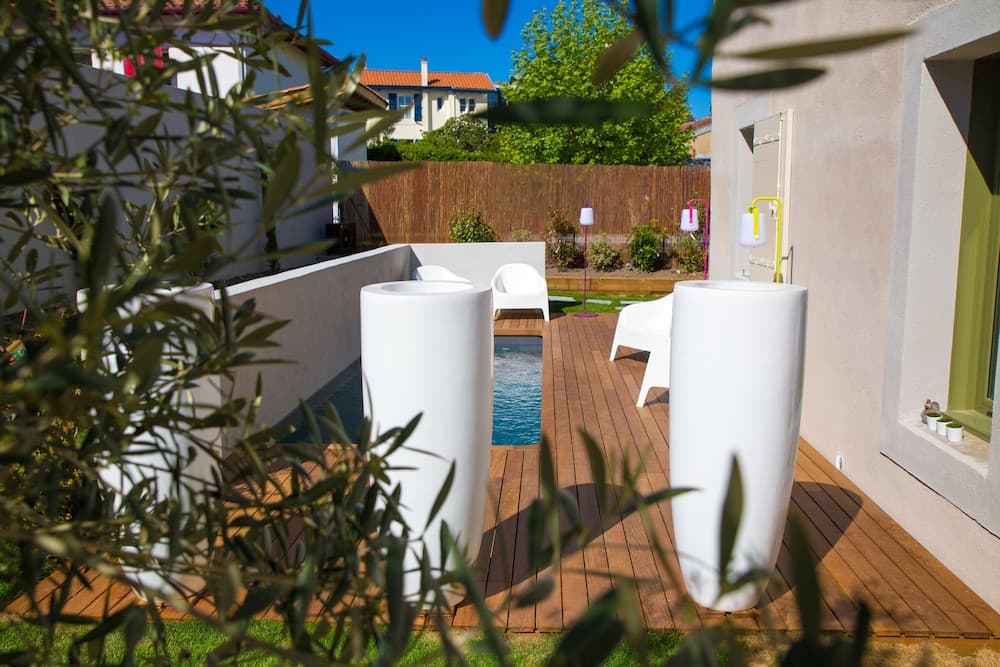 A serene private terrace features a small pool, modern white furniture, and lush greenery, creating an inviting outdoor retreat perfect for vacation rentals.