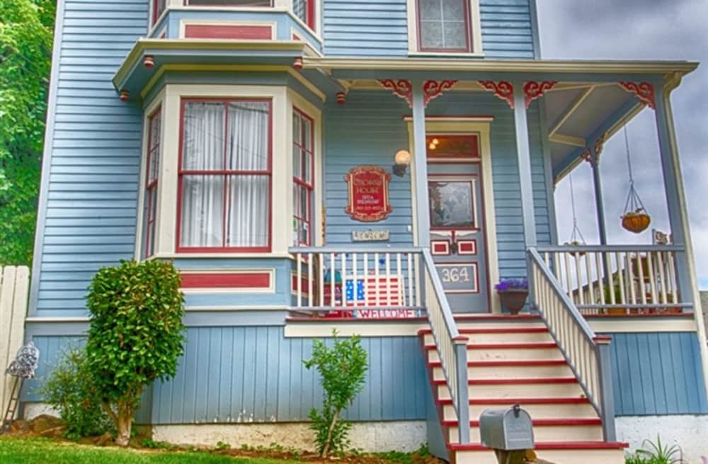 A charming blue Victorian house with red accents and a welcoming porch invites travelers to experience cozy accommodations in a picturesque neighborhood.