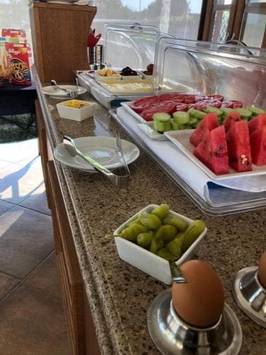 A vibrant buffet spread featuring fresh fruits, boiled eggs, and assorted breakfast items invites travelers to indulge in a hearty morning meal at an indoor dining area, perfect for a leisurely start to their day.