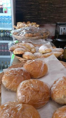 A cozy bakery scene displays an array of freshly baked pastries and breads on wooden baskets, inviting travelers to indulge in local culinary delights.