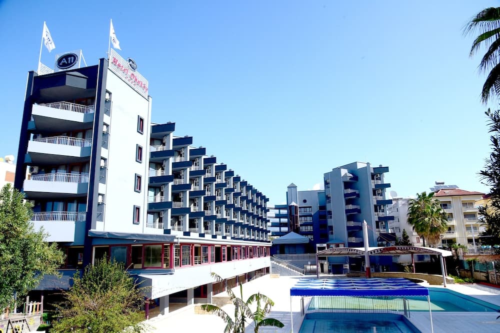 A vibrant resort complex featuring modern blue and white buildings, lush greenery, and inviting pools under a clear sky, ideal for family vacations and leisure travelers seeking relaxation.