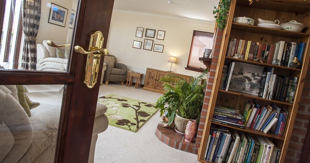 A cozy living room with plush seating, framed artwork, a bookshelf filled with travel guides, and a vibrant rug invites travelers seeking comfort and inspiration for their next adventure.