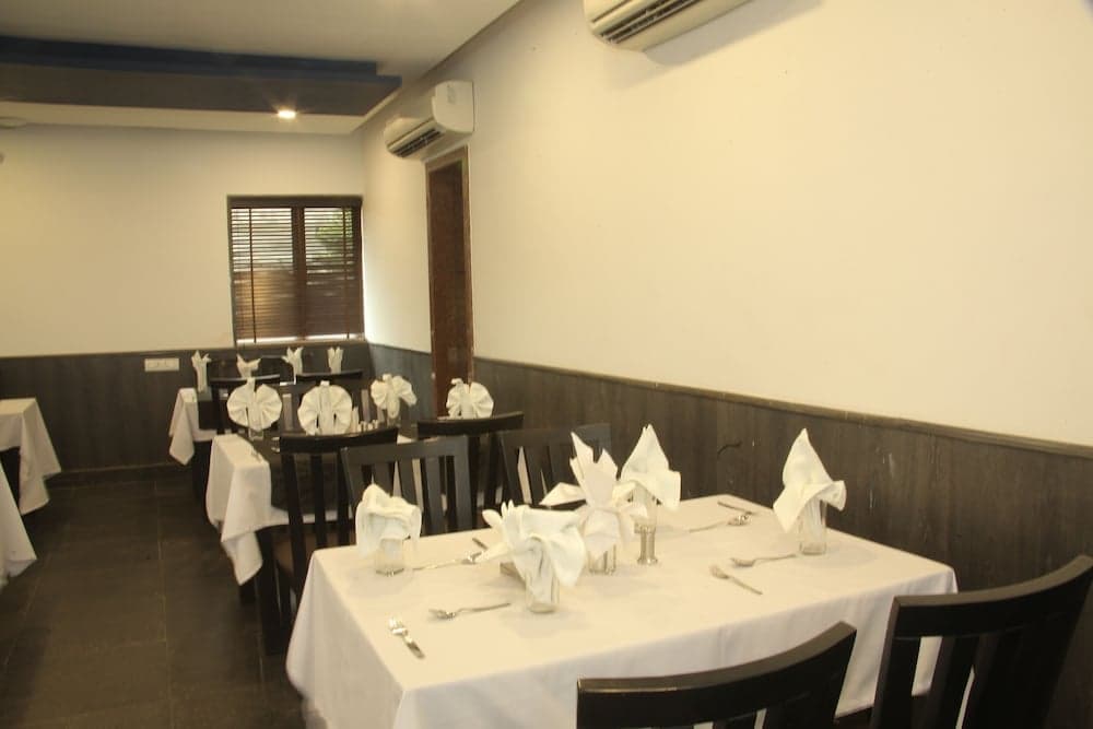 A cozy indoor dining area features neatly arranged tables with white tablecloths and folded napkins, set against a minimalist backdrop with wooden paneling, ideal for travelers seeking a quiet meal in a clean and organized restaurant setting.