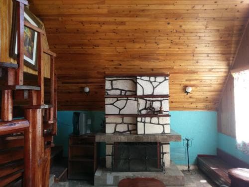 A cozy cabin interior features a rustic stone fireplace against wooden walls, creating a warm and inviting atmosphere perfect for a relaxing getaway.