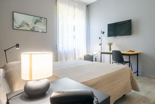 A cozy hotel room features a neatly made bed, modern desk setup with a vase of flowers, and soft lighting from a table lamp, creating a serene atmosphere ideal for travelers seeking comfort and relaxation.
