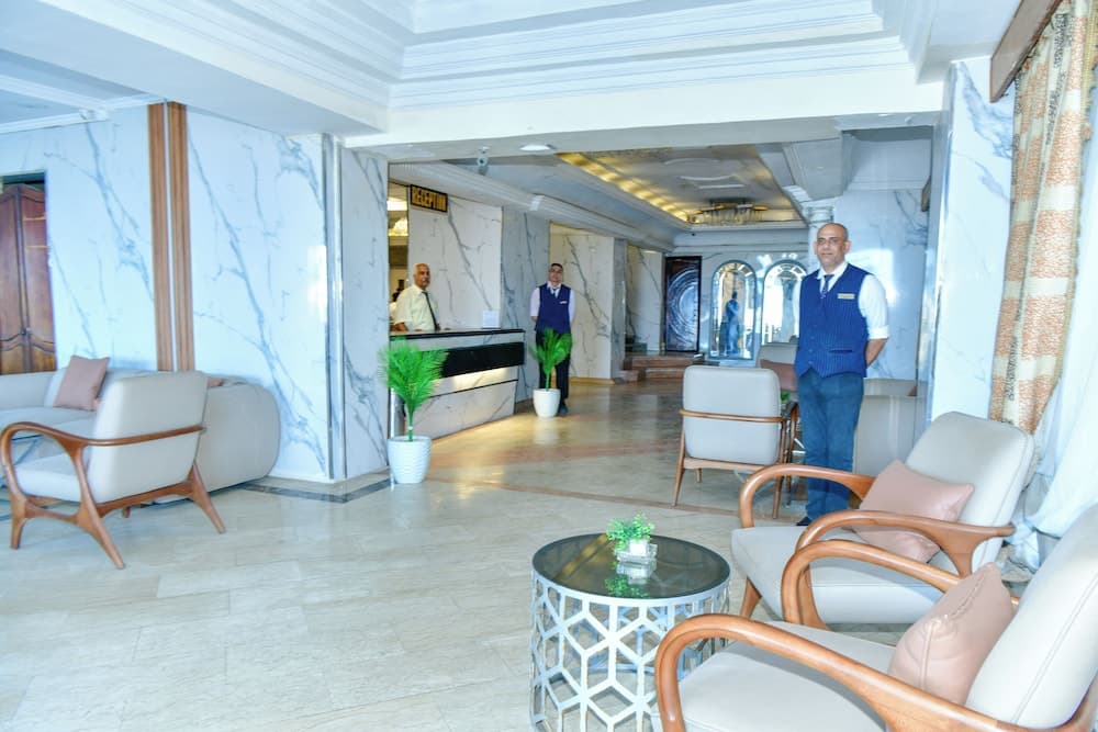A luxurious hotel lobby features elegant marble walls, comfortable seating areas, attentive staff in uniform, and a warm welcoming atmosphere ideal for travelers seeking upscale accommodations.