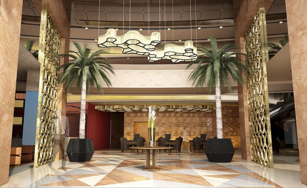 A luxurious hotel lobby features elegant marble floors, golden decorative screens, towering palm trees, and modern chandeliers, creating an inviting atmosphere ideal for travelers seeking upscale accommodations.