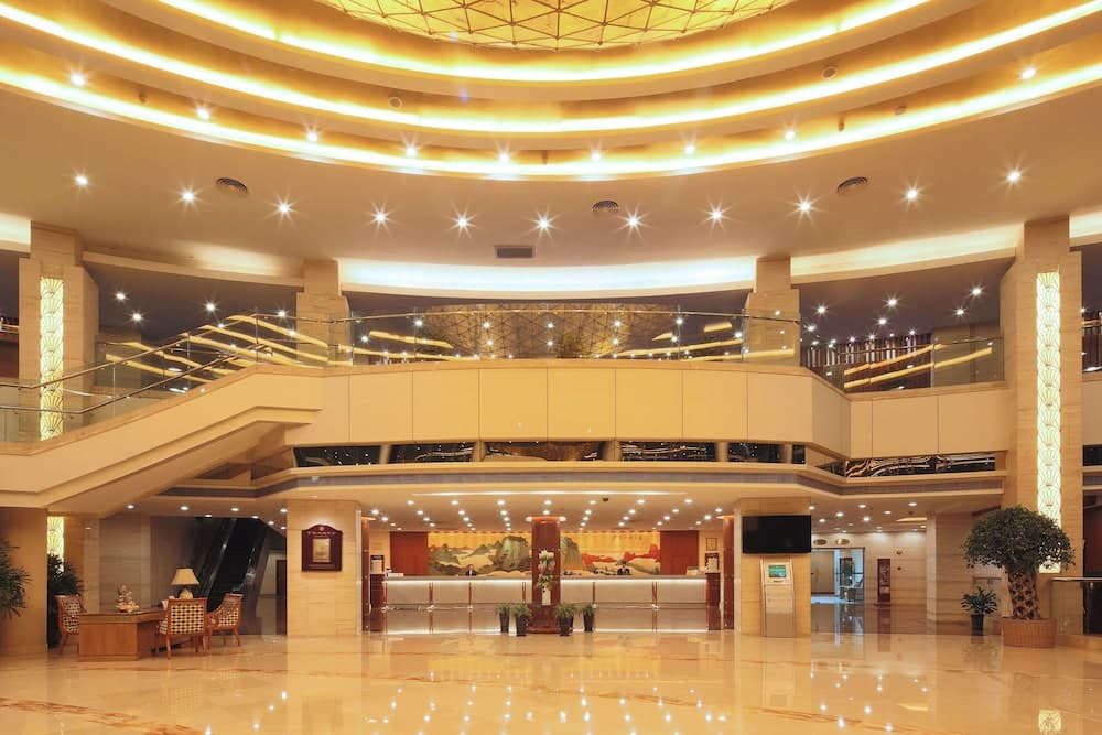 A luxurious hotel lobby features a grand staircase, sparkling lights, and elegant decor, creating an inviting atmosphere ideal for travelers seeking upscale accommodations.