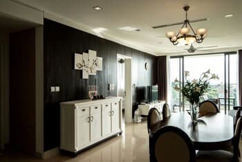A modern dining room with sleek furniture, dark wood paneling, and large windows offering a serene view, ideal for travelers seeking cozy accommodations with contemporary design elements.