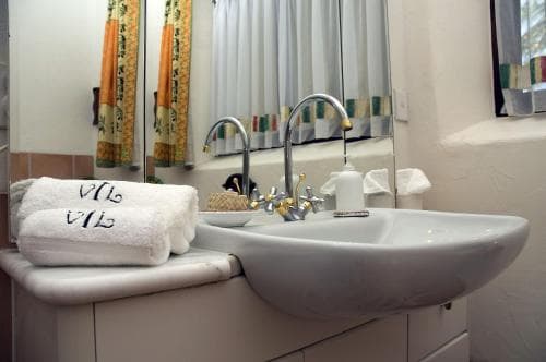 A cozy hotel bathroom features a sleek white sink, chrome fixtures, and neatly folded towels, creating a clean and inviting atmosphere ideal for travelers seeking comfort.