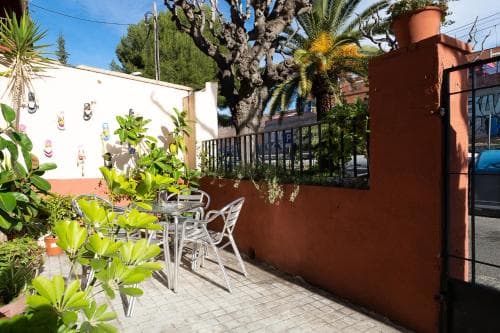 A cozy outdoor patio with vibrant greenery, colorful wall decorations, and a tiled table set against a warm terracotta wall, perfect for a relaxing vacation retreat in a sunny locale.