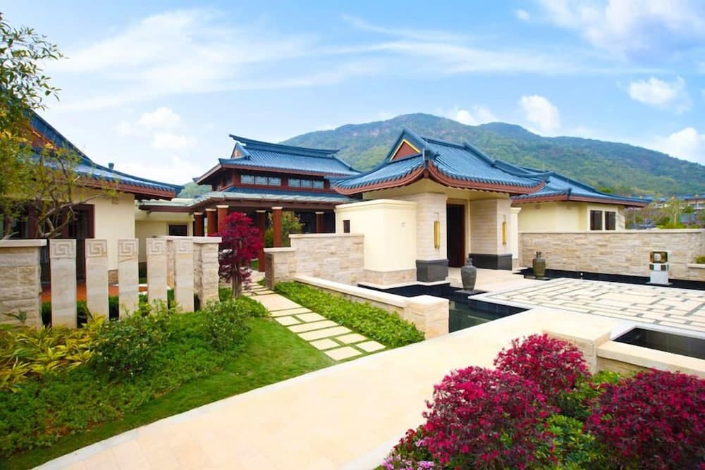 A serene luxury villa with traditional tiled roofs and lush gardens set against a mountain backdrop offers an ideal retreat for travelers seeking tranquility and cultural ambiance.