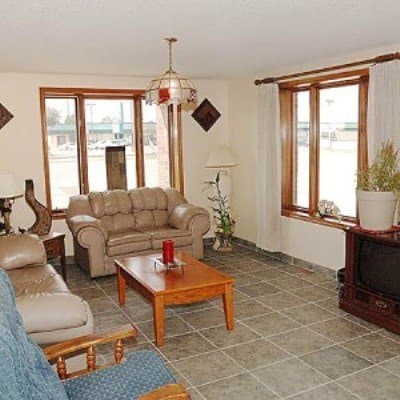 A cozy living room with beige sofas, wooden furniture, and large windows offers a warm and inviting atmosphere, perfect for travelers seeking comfort in a homey vacation rental setting.