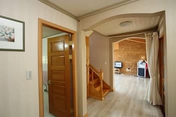 A cozy interior hallway with wooden stairs leads to a warmly lit living room featuring a TV and soft furnishings, ideal for travelers seeking a comfortable and inviting accommodation experience.