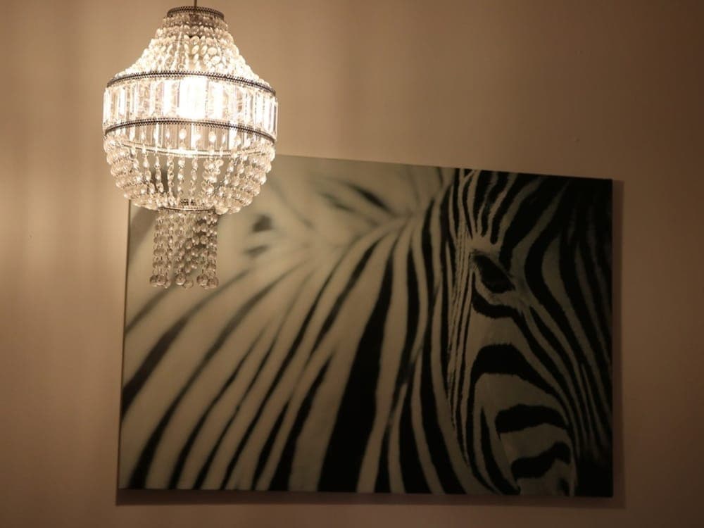 A cozy indoor setting features a sparkling crystal chandelier casting warm light over a striking black-and-white zebra canvas, ideal for travelers seeking elegant home decor inspiration.