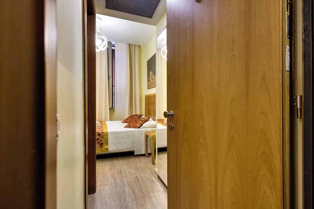 A cozy hotel room with warm lighting, wooden flooring, and neatly arranged bedding invites travelers seeking comfort and relaxation.