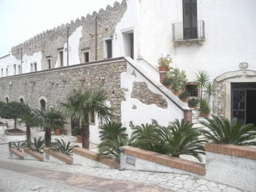 A charming Mediterranean courtyard features white-washed walls, stone staircases adorned with cacti and potted plants, creating a serene and inviting atmosphere ideal for cultural exploration and relaxation.