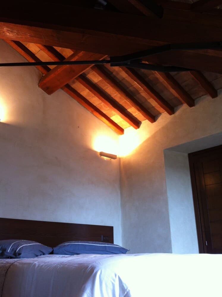 A cozy bedroom with rustic wooden beams and warm lighting creates an inviting atmosphere, perfect for travelers seeking a serene retreat in a charming countryside lodge.