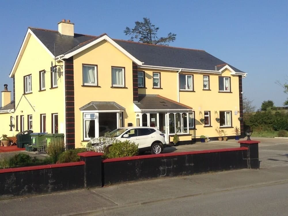 A charming yellow two-story house with a welcoming porch and neatly arranged potted plants exudes a cozy, inviting atmosphere ideal for travelers seeking a peaceful rural retreat.