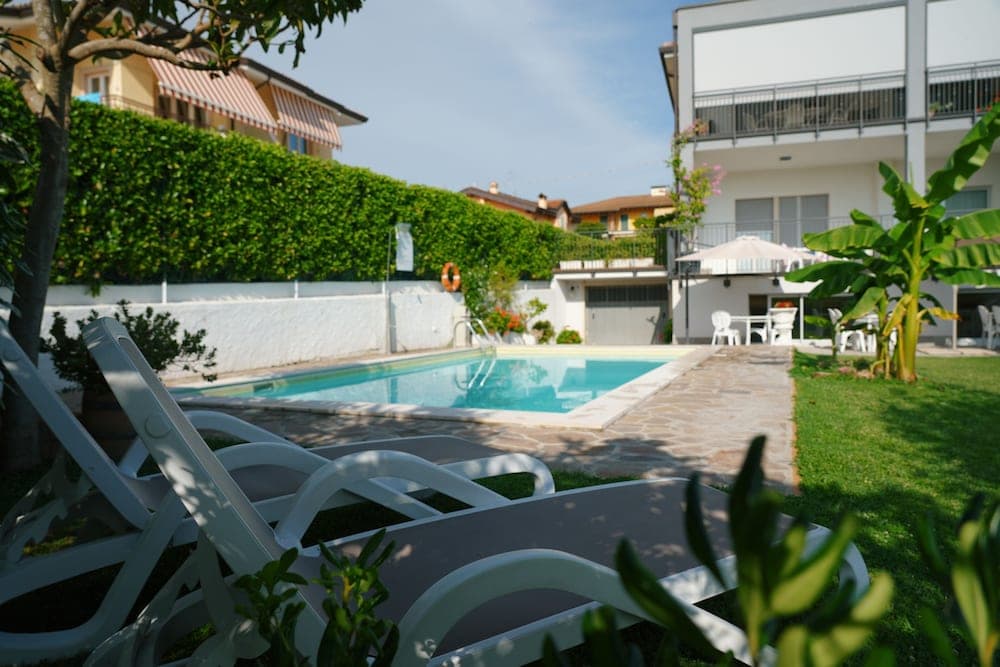 A serene residential poolside scene with lounge chairs, lush greenery, and modern buildings offers a relaxing vacation retreat perfect for leisure travelers seeking tranquility.