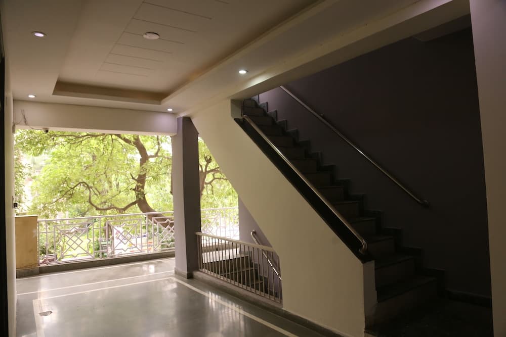 A modern indoor staircase with sleek railings leads to an open balcony overlooking lush greenery, creating a serene atmosphere ideal for travelers seeking a tranquil urban retreat.
