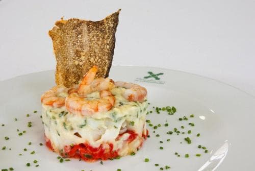 A gourmet shrimp dish artfully plated with vibrant layers of sauce and garnished with fresh herbs and a crispy bread slice, perfect for culinary enthusiasts seeking fine dining experiences.