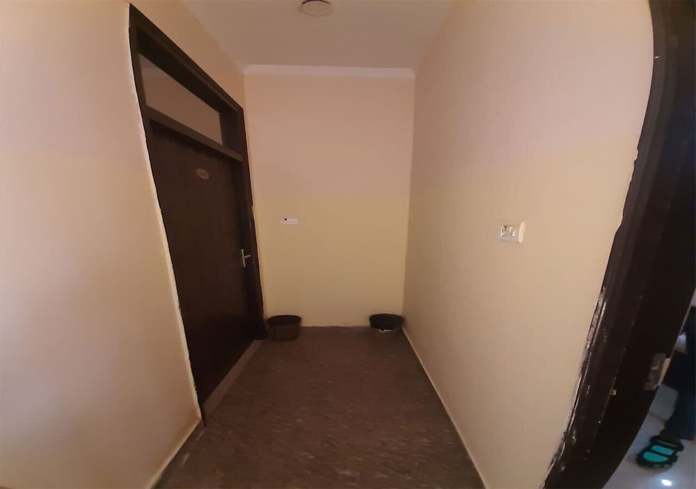 A cozy indoor hallway with cream-colored walls, a wooden door, and two small bowls on the carpeted floor creates a welcoming atmosphere ideal for travelers seeking a quiet accommodation space.
