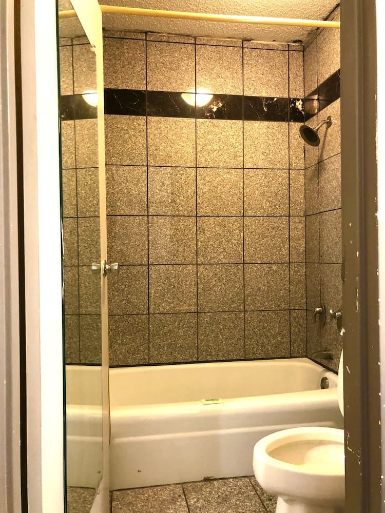 A compact bathroom with beige tiled walls, a bathtub, and a toilet, exudes a cozy and functional atmosphere ideal for travelers seeking practical accommodations.