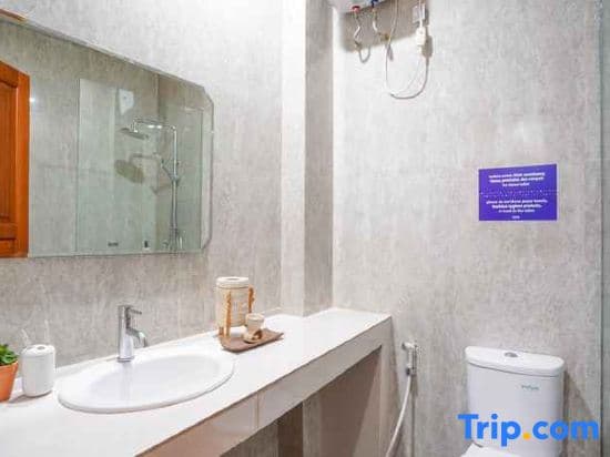 A clean, modern bathroom with a white vanity, sink, mirror, and toilet, featuring a purple informational sign on the wall, ideal for travelers seeking accommodations with well-maintained facilities.