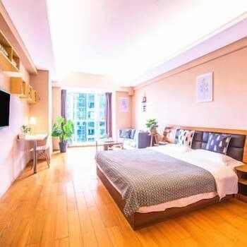 A cozy hotel room with warm wooden floors, a neatly made bed, and large windows offering a city view, ideal for travelers seeking comfort and relaxation during their urban getaway.