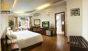A cozy hotel room with wooden floors, a neatly made bed, and a view of a vibrant outdoor scene through the window, ideal for travelers seeking comfort and relaxation.