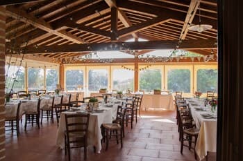 A serene dining area with wooden tables set under a high-beamed ceiling, surrounded by lush greenery, evokes a tranquil atmosphere ideal for intimate gatherings or eco-friendly retreats.