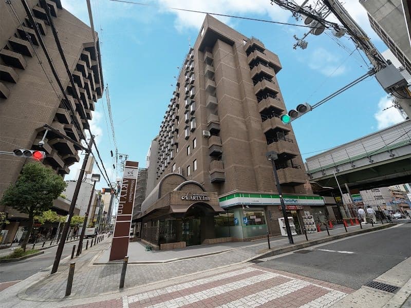 A bustling urban street in Osaka showcases the modern Shinsaibashi ARTY Inn under a clear blue sky, ideal for travelers seeking a vibrant city stay near local amenities and public transit.