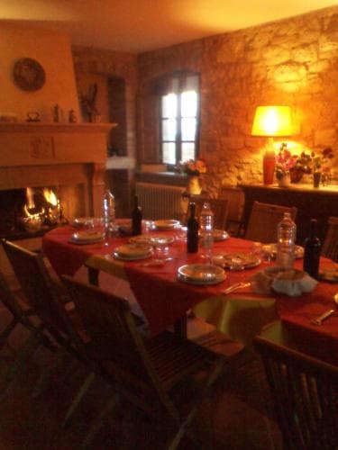 A cozy dining room with stone walls, a warm fireplace, and a set table creates an inviting atmosphere perfect for a rustic retreat or intimate dinner gathering.