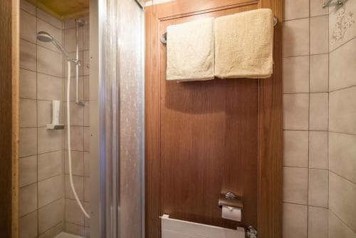 A cozy hotel bathroom features a tiled shower stall, wooden accents, neatly folded towels, and a warm ambiance, ideal for travelers seeking comfort during their stay.