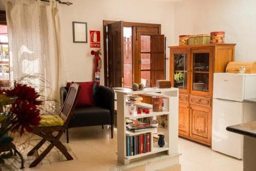 A cozy apartment interior featuring wooden furniture, vibrant decor, and natural light streaming through open doors, ideal for travelers seeking a warm and inviting short-term rental experience.