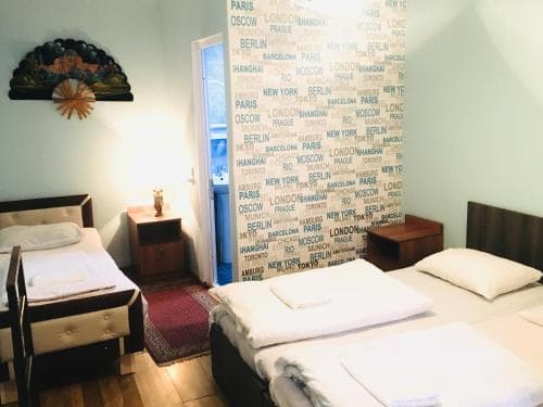 A cozy hotel room with wooden furniture, city-themed wallpaper, and warm lighting creates an inviting atmosphere ideal for travelers seeking comfort and a touch of global flair.