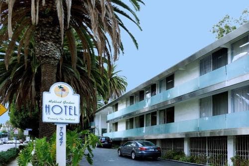 A sunny day at a mid-century motel with palm trees and a welcoming signboard creates a nostalgic atmosphere ideal for travelers seeking retro charm and coastal vibes.