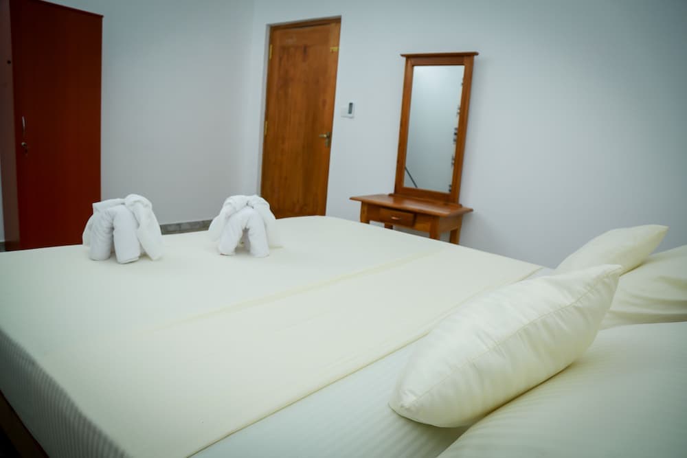 A cozy hotel room features a neatly made bed adorned with towel animals, a wooden vanity with a mirror, and soft lighting, ideal for travelers seeking comfort and relaxation.