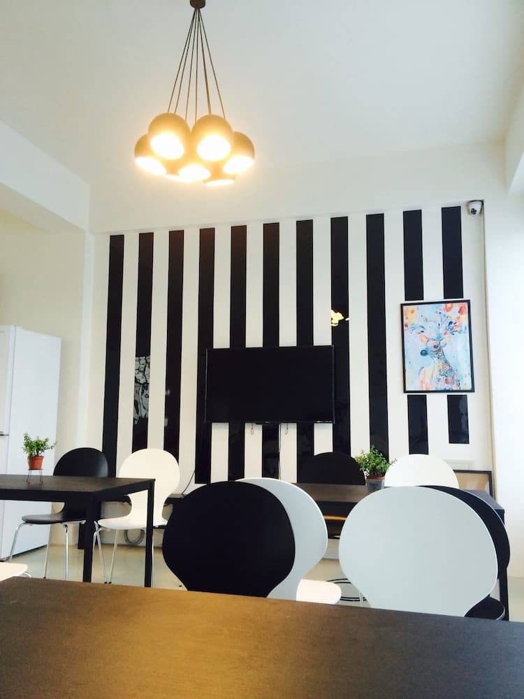 A modern dining area features black-and-white striped walls, sleek round chairs, and a vibrant deer painting, creating an artistic and cozy atmosphere ideal for travelers seeking stylish accommodations.
