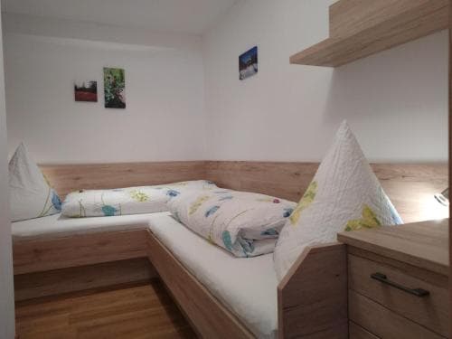 A cozy, modern bunk bed room with wooden furnishings and soft bedding creates a welcoming atmosphere ideal for travelers seeking comfortable accommodation in a compact space.