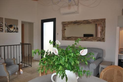 A cozy living room with soft furnishings, a decorative mirror, and lush greenery creates an inviting atmosphere, perfect for travelers seeking a comfortable and stylish accommodation.