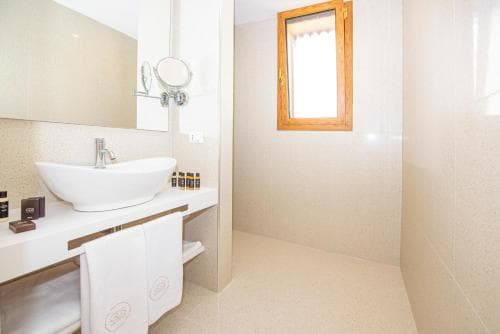 A serene hotel bathroom features a modern vessel sink, neatly folded towels, and a small window, ideal for travelers seeking comfort and cleanliness.
