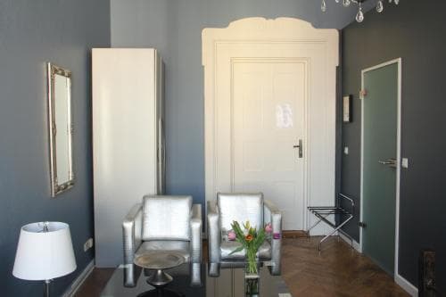 A cozy hotel room hallway features modern silver chairs, a floral centerpiece, and elegant decor, creating an inviting atmosphere ideal for travelers seeking comfort and style.