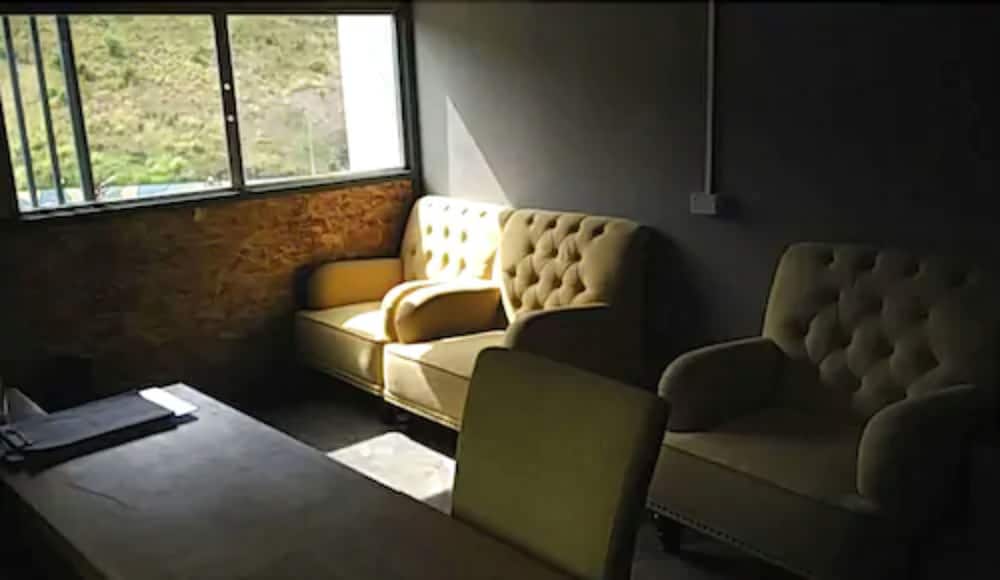 A cozy lounge area with plush tufted armchairs bathed in soft sunlight from a window overlooking greenery, ideal for travelers seeking a relaxing retreat or business meeting space.