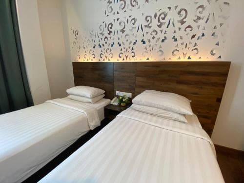 A cozy hotel room features two neatly made beds with striped linens against a decorative patterned wall, creating a serene and inviting atmosphere ideal for travelers seeking comfort and relaxation.