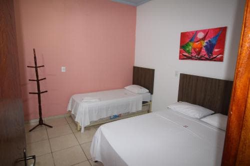 A cozy hotel room with two neatly made beds, a vibrant wall painting, and a wooden coat rack creates a welcoming atmosphere ideal for budget travelers seeking comfort.