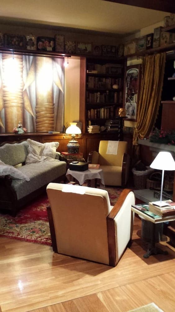 A cozy living room with warm lighting, wooden floors, vintage furniture, and bookshelves exudes a nostalgic charm, perfect for travelers seeking a serene retreat or history enthusiasts exploring classic interior design.