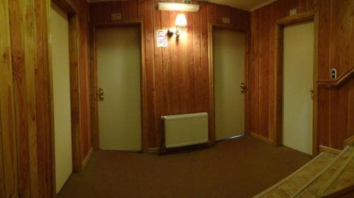 A cozy hotel corridor with wooden paneling, carpeted floors, and warmly lit ambiance offers travelers a nostalgic and inviting atmosphere for their stay.